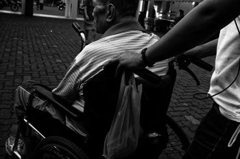 Ein Mann sitzt im Rollstuhl und wird geschoben