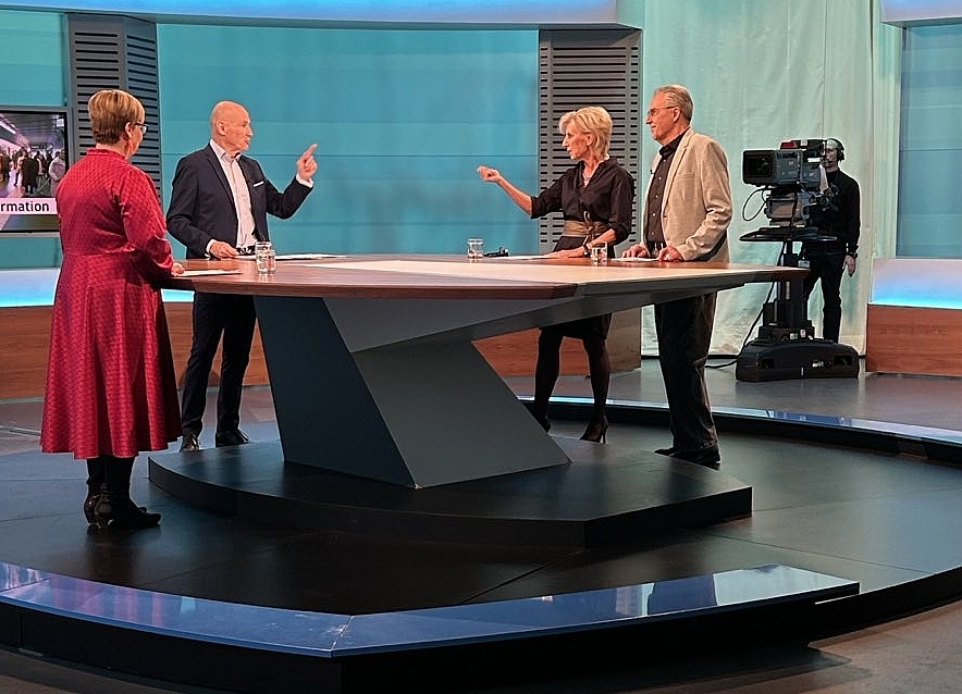 Volksanwältin Gaby Schwarz steht im ORF Studio neben einem Beschwerdeführer und spricht mit Moderator Peter Resetarits. 