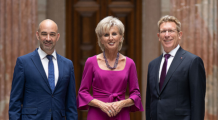 Volksanwalt Christoph Luisser, Volksanwältin Gaby Scharz, Volksanwalt Bernhard Achitz stehen nebeneinander, in der Säulenhalle des Österreichischen Parlaments.