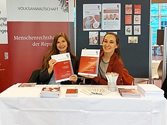 Messestand mit Infomaterial und 2 Frauen