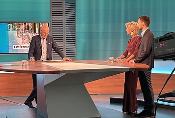 Volksanwältin Gaby Schwarz im ORF Studio bei der Sendung Bürgeranwalt. Sie steht mit dem Moderator Peter Resetarits und einem Beschwerdeführer an einem Tisch.