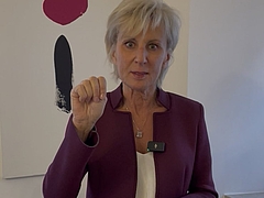 Ombudswoman Gaby Schwarz stands in her office and shows the SOS hand signal in case of violence.