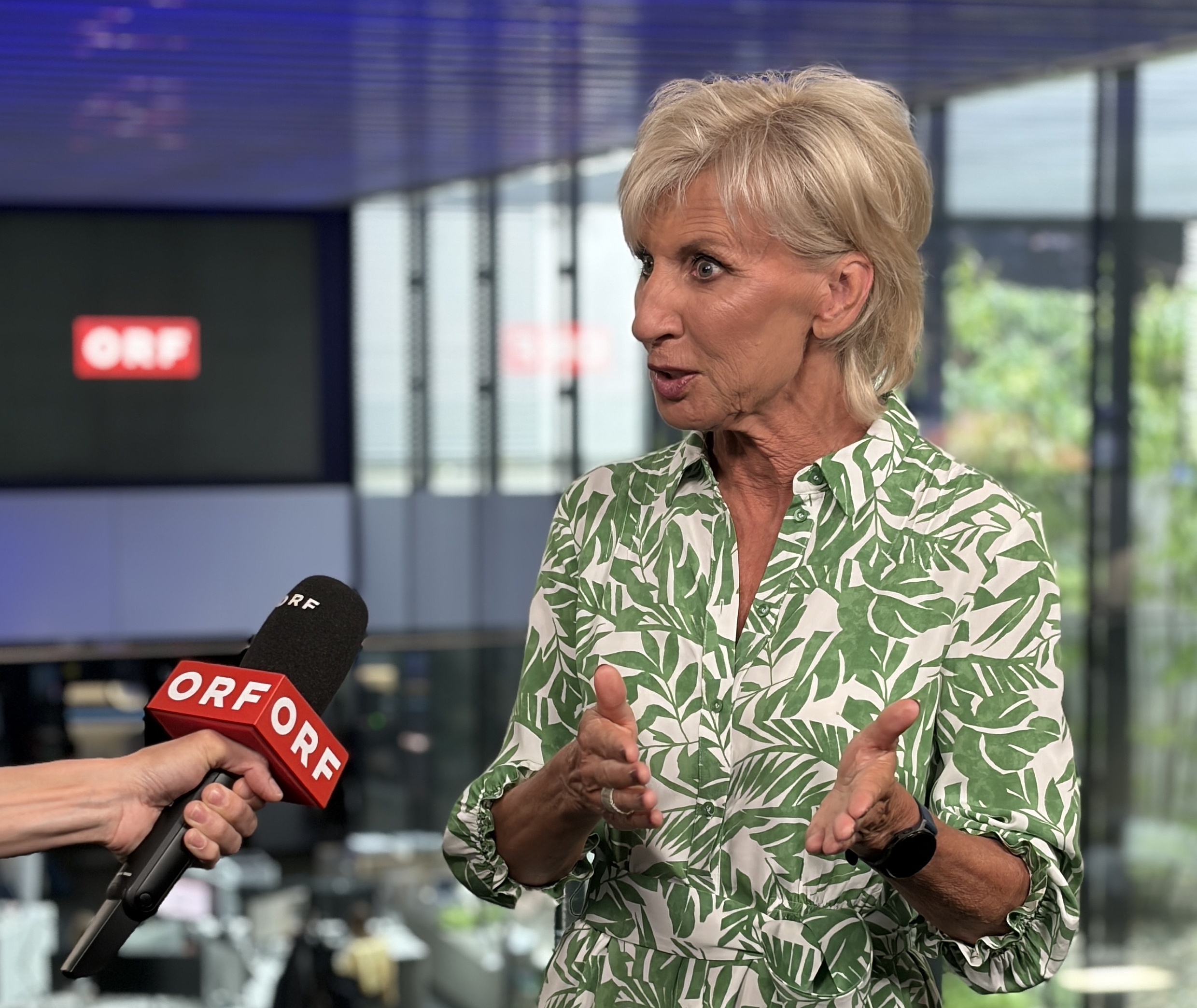 Volksanwältin Gaby Schwarz in einem grün-weißen Kleid, wird von einer ORF Redakteurin interviewt und spricht in ein Mikrofon.