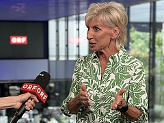 Volksanwältin Gaby Schwarz in einem grün-weißen Kleid, wird von einer ORF Redakteurin interviewt und spricht in ein Mikrofon.