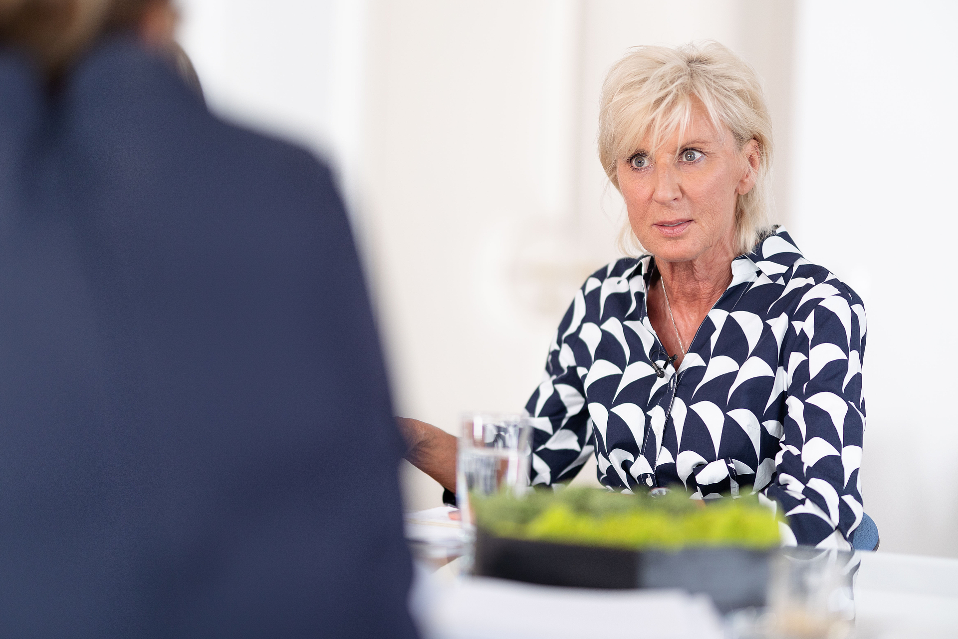 Volksanwältin Gaby Schwarz sitzt an einem Tisch, im Gespräch mit einer anderen Person