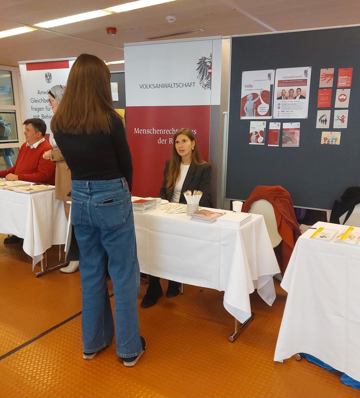 Frau spricht mit einer Studentin beim Messestand