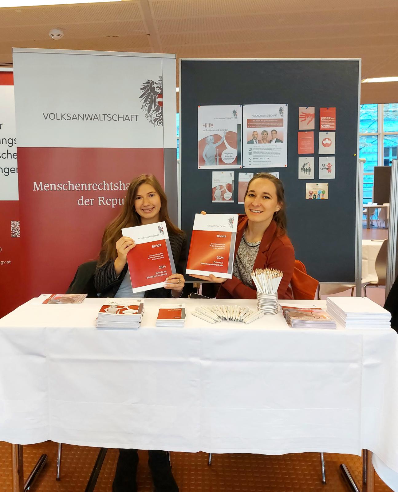 Messestand mit Infomaterial und 2 Frauen