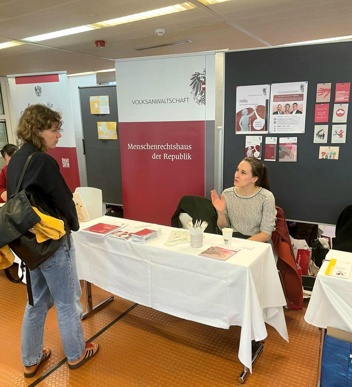 Frau spricht mit einer Studentin beim Messestand