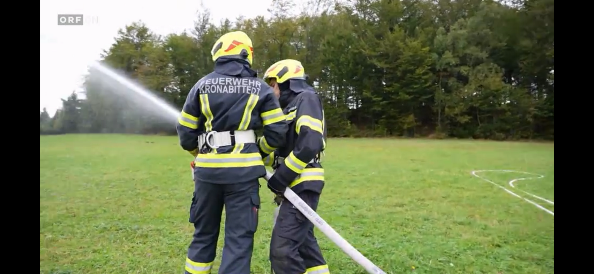 Mitglieder der Freiwilligen Feuerwehr mit einem Löschschlauch bei einer Übung