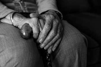 Die Hände eines älteren Menschen halten einen Gehstock