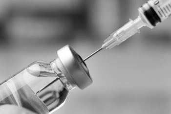 Spritze zieht Impfstoff aus Ampulle auf. 