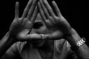 Ein Mann hält seine Hände vor sein Gesicht, die Handflächen nach außen und formt mit ihnen ein Dreieck
