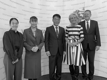 Two Korean women and a Korean man, an Austrian woman and an Austrian man standing in front of the presswall of the Austrian Ombudsman Board.