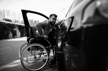 Ein Mann im Rollstuhl steigt in ein Auto.