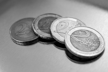 Vier 2-Euro-Münzen auf glatter Oberfläche.